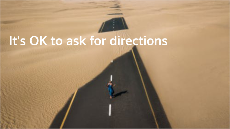 Woman walking sand swept tar road lost in desert